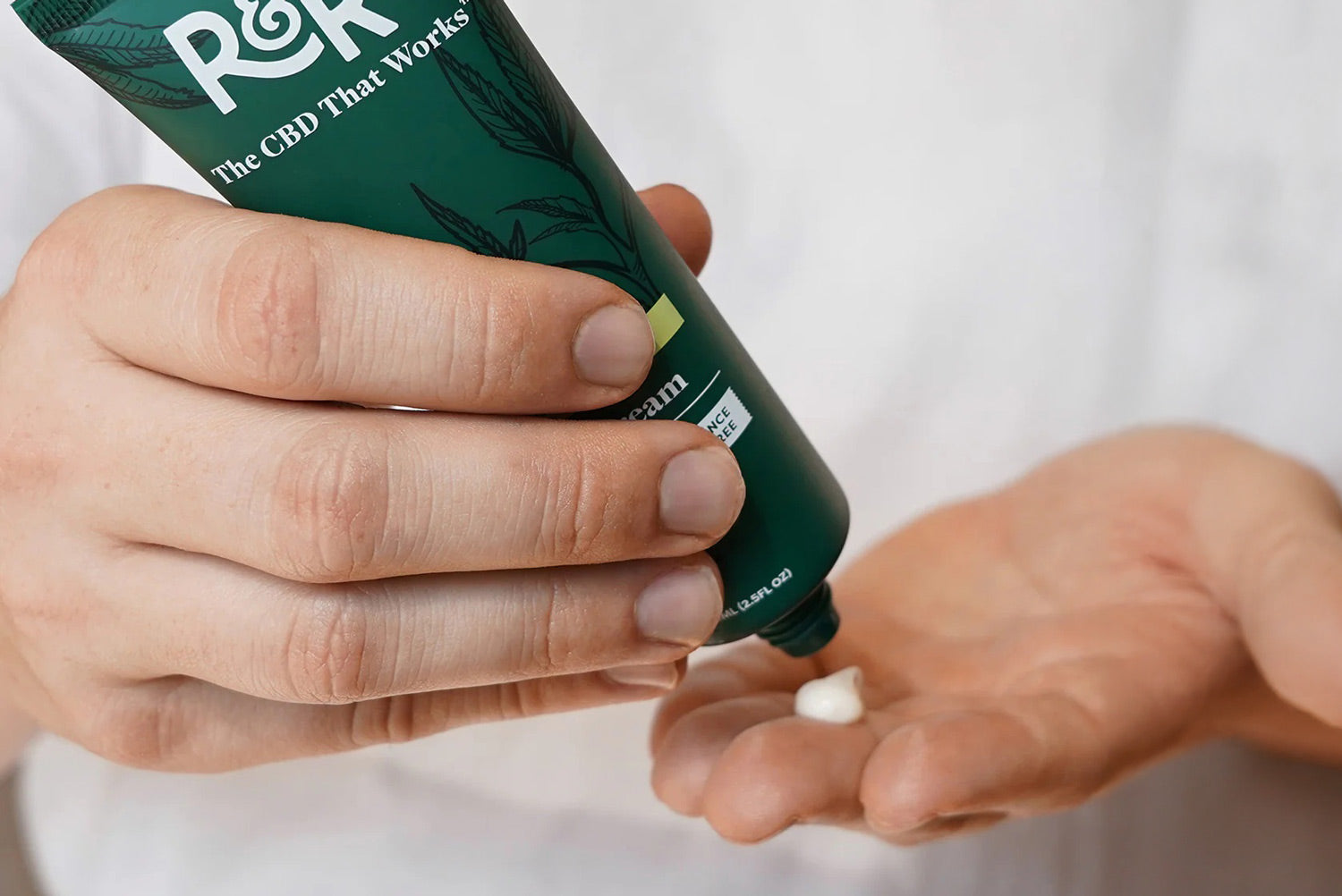 Person holding a tube of R&R Medicinals CBD Pain Cream