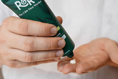 Person holding a tube of R&R Medicinals CBD Pain Cream